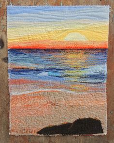 a piece of art that has been made to look like an ocean scene with the sun setting