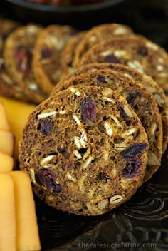 several cookies and cheeses on a plate with other food items in the back ground