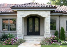 a house with flowers in front of it and a walkway leading to the front door