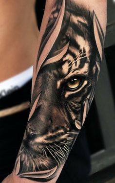 a black and white tiger tattoo on the left arm with an orange eyeshadow