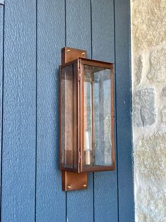 an old fashioned lantern on the side of a blue building with stone wall and door