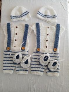 two crocheted baby clothes and hat are laid out on a white tablecloth