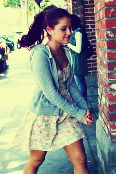 a young woman leaning against a brick wall