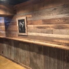 an empty room with wood paneling on the wall and pictures hanging on the wall