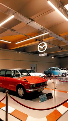 several old cars are on display in a museum with orange and white checkered flooring