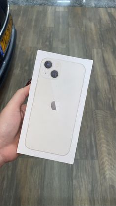 a person holding an apple phone in their left hand with the box on it's side