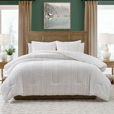 a bed with white comforter and pillows in a room