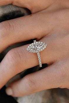 a woman's hand with a diamond engagement ring on her left hand and an oval shaped