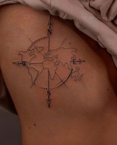 a woman's back with a compass tattoo on her left side ribcage