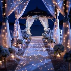 an outdoor wedding setup with white flowers and candles on the aisle, lit up by fairy lights