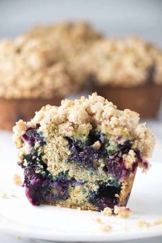 a close up of a muffin with blueberries on it and another muffin in the background