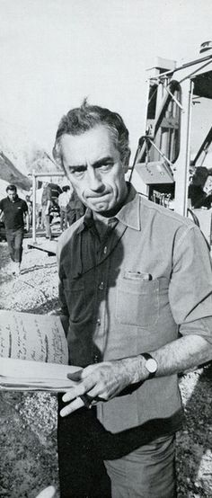 black and white photograph of a man holding an open book in front of construction equipment