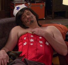 a man in a costume laying on a couch with his face painted like an american flag