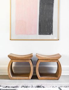 two wooden stools sitting in front of a painting