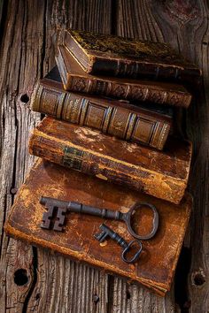 an old key and some books sitting on top of a wooden table next to each other