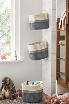 two baskets are hanging on the wall next to a stuffed animal