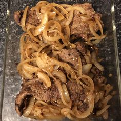 meat and noodles are being cooked in a glass dish