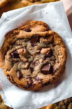 a chocolate chip cookie sitting on top of a piece of wax paper