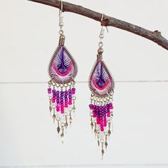 These handmade classy and beautifully woven dangly earrings come in an array of gorgeous colours. They feature a woven teardrop, similar in style to a peacock feather, and are finished with co-ordinating beads and silver embellishments.  Ideal for a night out or for dressing up your unique boho look! These lovely earrings are sourced from ethical and small family businesses, the eye-catching variation of colours, beads and contemporary detailing enhance the earrings to make each pair unique. App Purple Teardrop Bohemian Earrings, Multicolor Handwoven Teardrop Earrings, Handwoven Multicolor Teardrop Earrings, Woven Drop Earrings, Handwoven Teardrop Earrings For Festivals, Handmade Teardrop Bohemian Tassel Earrings, Bohemian Handmade Teardrop Tassel Earrings, Pink Beaded Teardrop Earrings, Handmade Teardrop Tassel Earrings For Gift