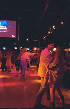 people are dancing on the dance floor in front of a projector screen at night