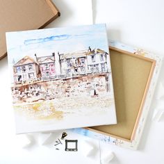 a watercolor painting of some houses on the beach next to a box with keys