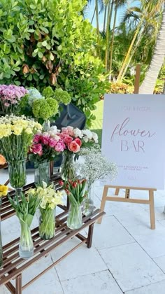 flowers are displayed in vases on a wooden table with a sign that says flower bar