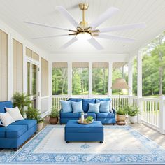 a blue couch sitting on top of a white rug under a ceiling fan in a living room