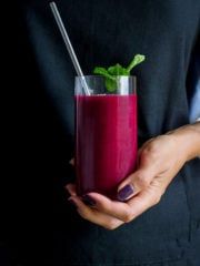 a woman holding a drink in her hand with a straw and garnish on the rim