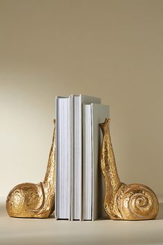 two golden snail bookends sitting next to each other