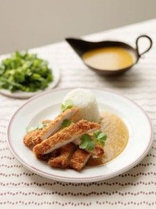 a white plate topped with food next to a bowl filled with sauce and lettuce