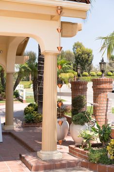 a gazebo with potted plants and trees in the background