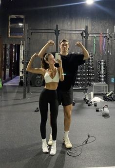 a man and woman standing next to each other in front of a gym equipment rack