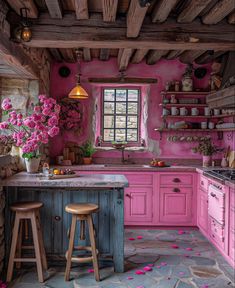 a kitchen with pink painted walls and wooden floors, two stools in front of the island