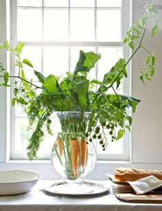 an open magazine with a vase filled with carrots and greenery on top of a table