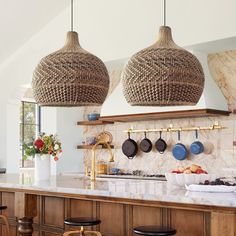 a kitchen with two hanging lights above the counter and stools in front of it