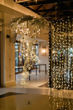 a chandelier hanging from the ceiling in front of a glass door with lights on it