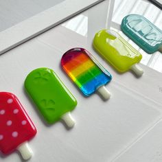 four popsicles in different colors are lined up on a white surface with polka dots