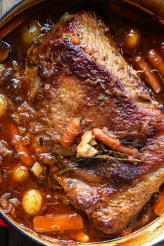 a pot filled with meat and vegetables on top of a wooden table