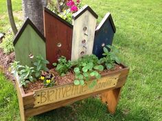 a wooden planter filled with lots of different colored birdhouses sitting on top of grass