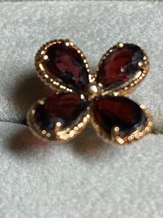 Unique 10K yellow gold garnet flower ring for your consideration. This adorable ring is hallmarked 10K and guaranteed to be such. It features a 4 petal flower with each petal made up a prong set teardrop garnet. The garnets measure approximately 8mm x 5.3 mm. The center of the flower is a small gold ball. Under each of the petals is small unfilled or shadow petal which gives the setting height. There is beautiful detailing on both the setting and the band. The setting measures 15.7mm x 15.3mm. I Formal Red Flower Ring, 14k Gold Formal Flower Ring, Formal 14k Gold Flower Ring, Formal Hallmarked Flower Ring, 4 Petal Flower, Petal Ring, Petal Flower, Unique Ring, Flower Ring