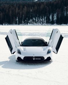 a white sports car with its doors open in the snow