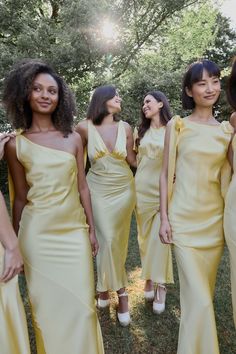 four beautiful women in yellow dresses posing for the camera with their hands on their hips