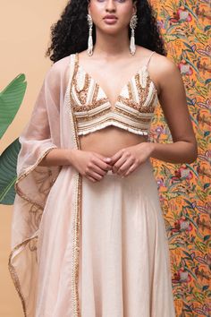 Editor's Note The fully embroidered panel blouse with a deep v-neck comes in with a rose gold lehenga along with a rose gold embroidered dupatta. Color: Rose gold Fabric: Cotton Occasion: Festive and Wedding Guest Components: Lehenga, blouse and dupatta Disclaimer: Product color may slightly vary due to photographic lighting sources or your monitor setting. Care: Dry Clean Only About the Designer Rishi & Vibhuti label combines traditional elements with modern aesthetic uniquely to create chic oc Festive V-neck Lehenga With Dupatta, Festive V-neck Lehenga For Reception, Reception Palazzo Set With Gold Embroidery, Diwali Lehenga With Resham Embroidery And V-neck, V-neck Lehenga With Resham Embroidery For Diwali, Bollywood Style V-neck Sets For Reception, Designer V-neck Lehenga For Festivals, Festive V-neck Sets For Reception, Anarkali Style Lehenga With V-neck And Resham Embroidery