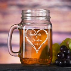 a mason jar with a heart etched on it next to some grapes and other fruit