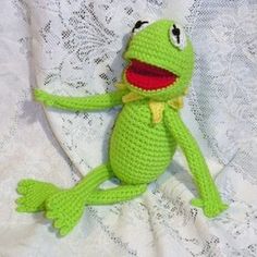 a crocheted frog sitting on top of a bed