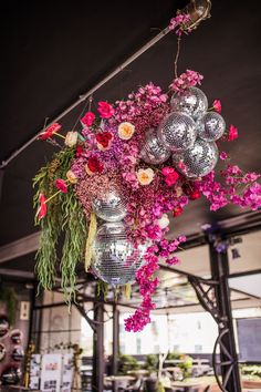 a vase filled with lots of pink flowers on top of a wooden table next to a mirror ball