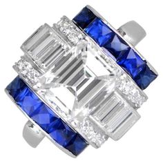 a blue and white ring with three baguets on it's sides, surrounded by diamonds