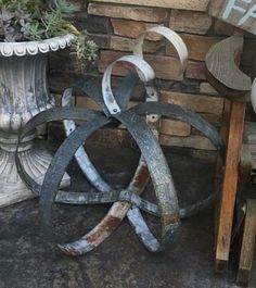 an assortment of metal objects sitting next to a brick wall and potted planter