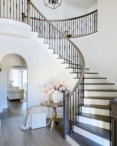 there is a vase with flowers on the table in front of the stair case that leads up to the second floor