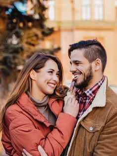 a man and woman smile at each other as they stand in front of a building